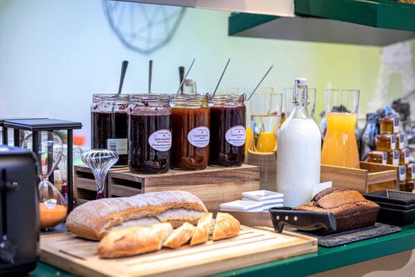 A breakfast counter with various food items and beverages, including jars of jam, a loaf of bread, and a bottle of milk.