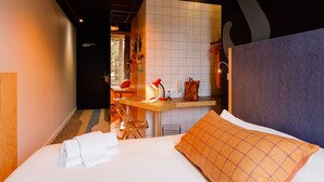 A hotel room with a bed, a desk, a chair, and a bathroom visible through an open door. - Greet Hotel  Lyon Confluence (Lyon)
