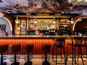 A bar area with stools, a bar counter, and shelves stocked with bottles. - Greet Hotel  Lyon Confluence (Lyon)