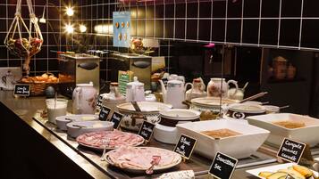 Un buffet con diverse pietanze e utensili, tra cui carni, formaggi e salse, esposte su un bancone con cartelli che indicano i piatti.
