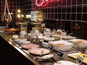 A buffet with various food items and utensils, including meats, cheeses, and sauces, displayed on a counter with signs indicating the dishes. - Greet Hotel  Lyon Confluence (Lyon)