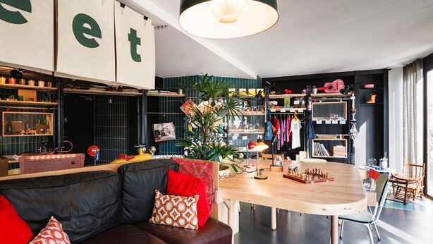 A modern living room with a leather sofa, wooden dining table, and a large plant. - Greet Hotel  Lyon Confluence (Lyon)