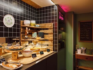 Un bancone di pasticceria con diversi prodotti da forno e una lavagna con il menu.