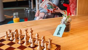 A chessboard with pieces on a wooden table, a small potted plant, and a 'greet' tag. - Greet Hotel  Lyon Confluence (Lyon)