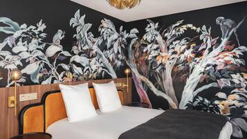 Un dormitorio con una cama grande, una mesita de noche, una lámpara de pared y un mural de árboles y flores.