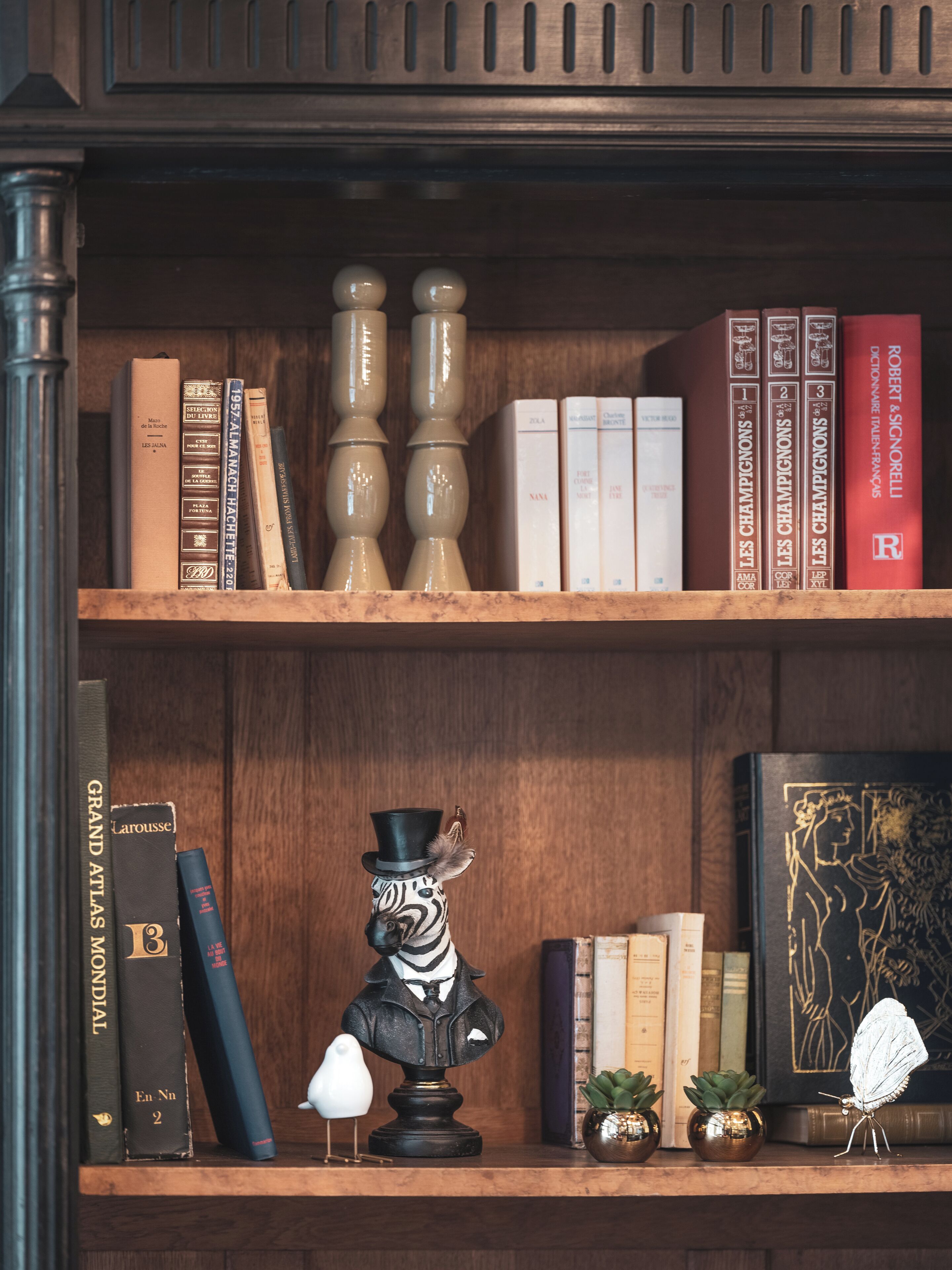 Una estantería con libros, adornos y un busto.