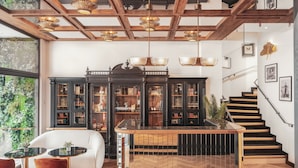 Un intérieur moderne avec un plafond en bois, un bar central aux couleurs noir et or, un canapé blanc et un escalier.