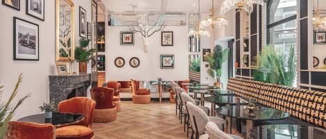 Un interior moderno con piso de madera en patrón de espiga, una variedad de asientos que incluyen sofás y sillones, y diversos adornos en las paredes.