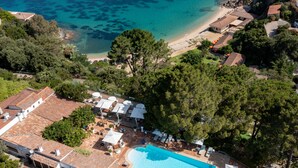 Vista aérea de un resort con piscina, playa y vegetación circundante.