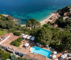 Vista aérea de um resort com piscina, praia e vegetação ao redor.