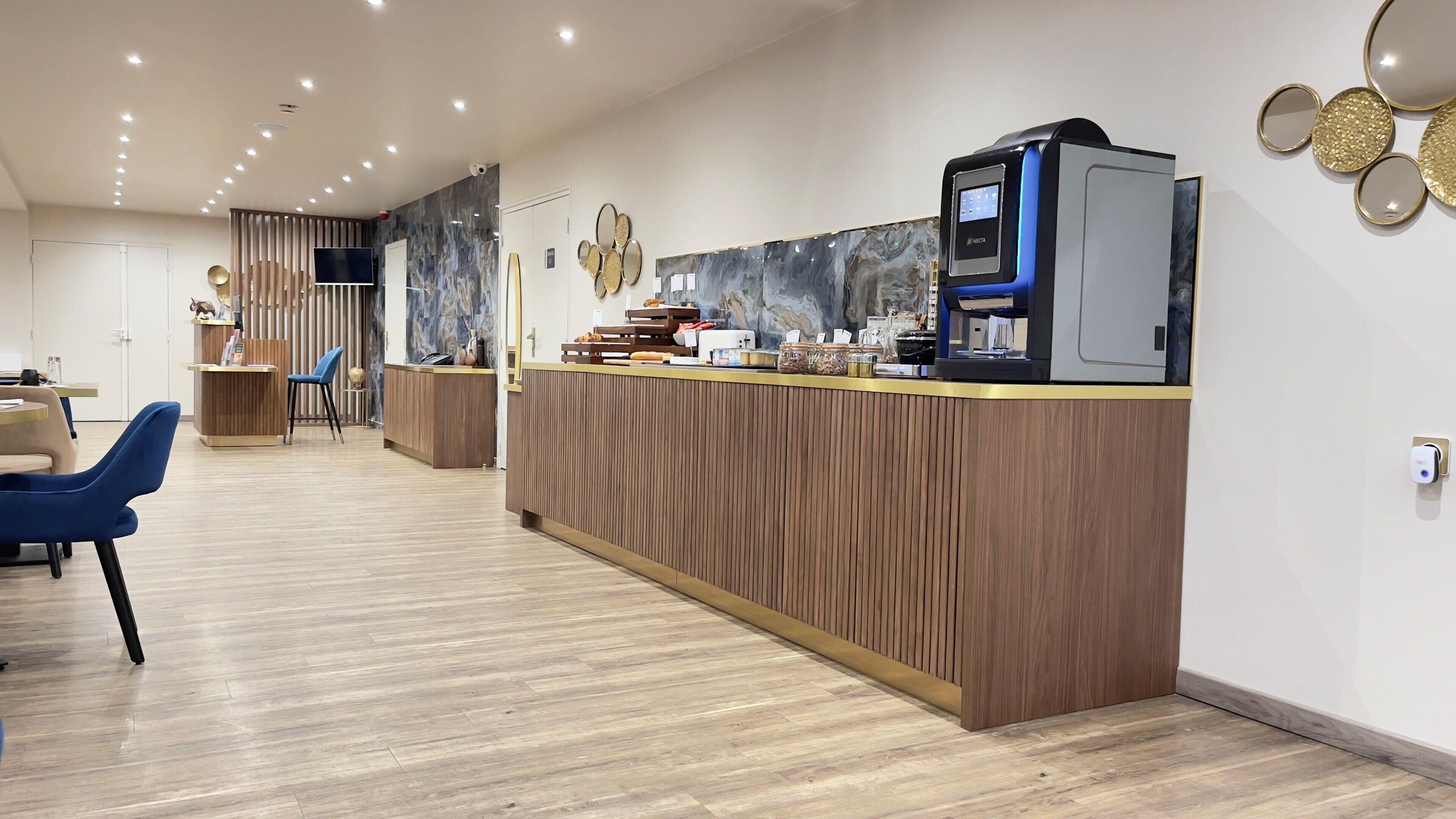 A modern reception area with a wooden reception desk, a flat-screen TV, and a coffee machine.