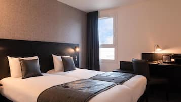 A hotel room with a large bed, a desk, and a chair.