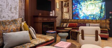 Un salon chaleureux avec un canapé à motifs, un fauteuil blanc et un vitrail.