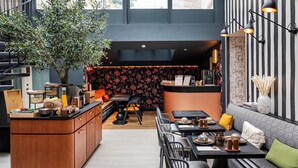 A modern interior with a wooden bar, seating area, and a staircase. - Hôtel Hiro (Paris)