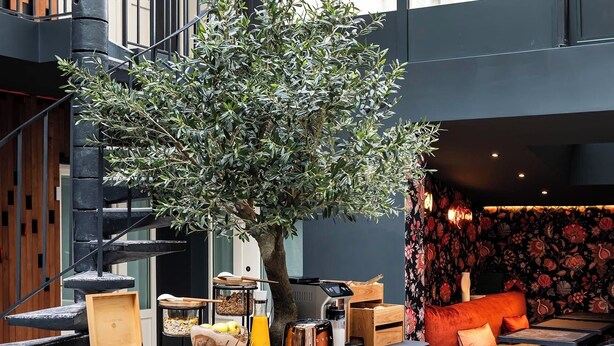 A modern interior with a central wooden island, black chairs, and a staircase. - Hôtel Hiro (Paris)