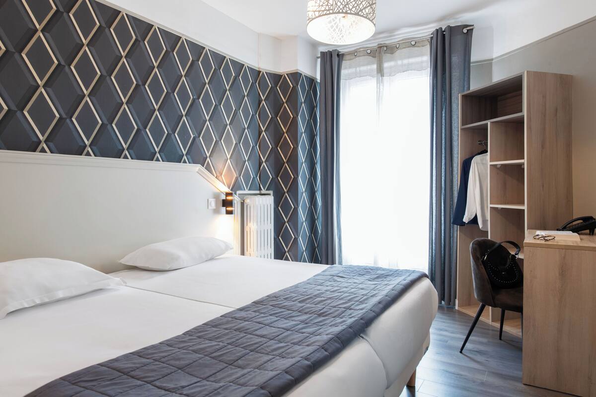 Een hotelkamer met een groot bed, een garderobe, een bureau en een raam met gordijnen.