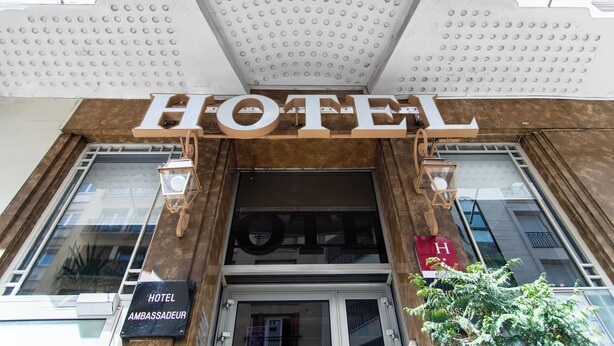 A hotel entrance with a large sign reading "HOTEL" and a smaller sign below stating "HOTEL AMBASSADEUR". - Hôtel Ambassadeur (Paris)