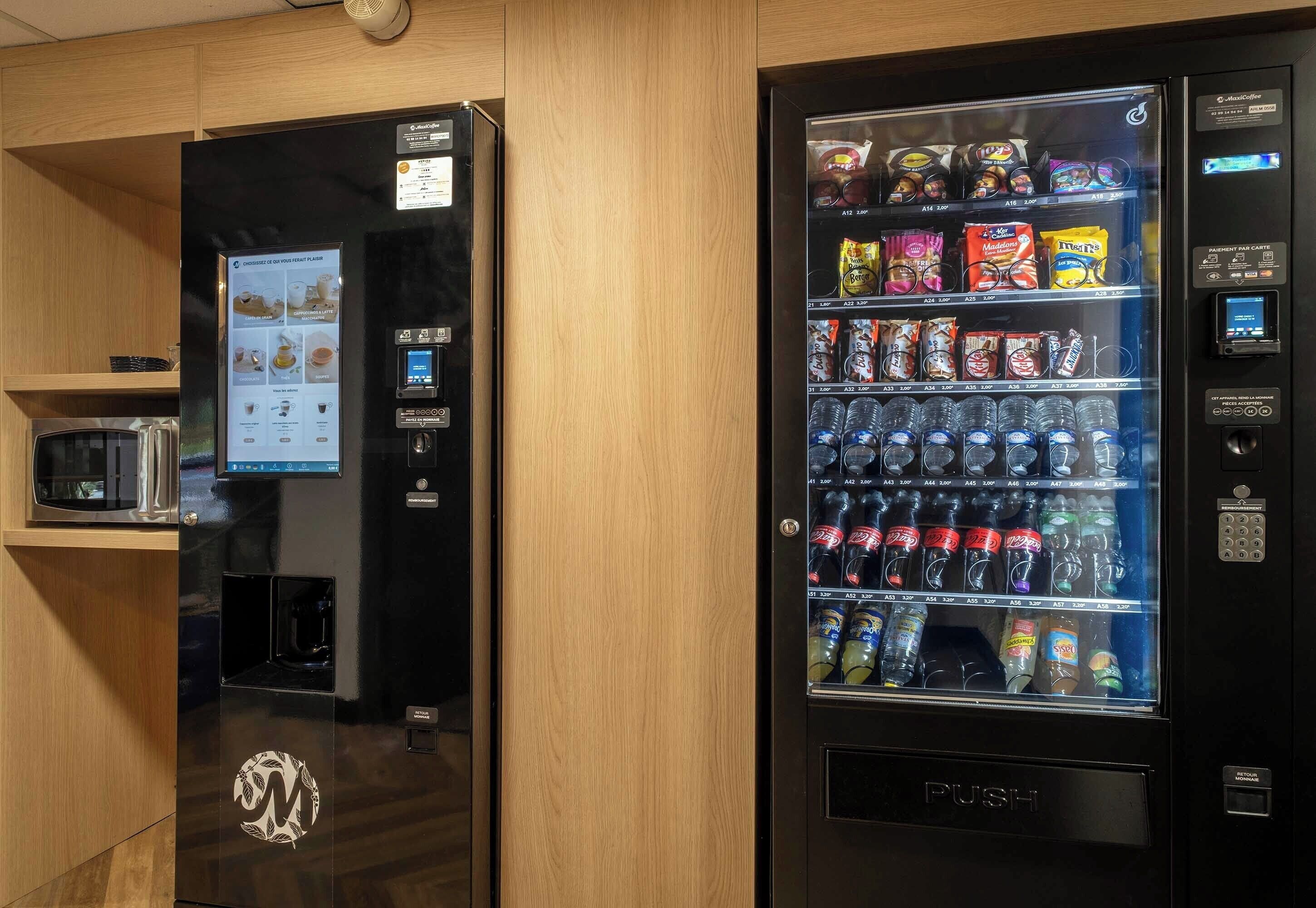 Two vending machines with snacks and drinks, a microwave, and a digital menu display.