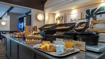 A breakfast buffet with croissants, scrambled eggs, and orange juice.