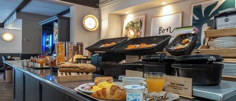 Un buffet de petit-déjeuner avec des croissants, des œufs brouillés et du jus d’orange.