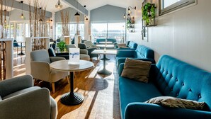 A modern lounge area with seating, a coffee table, and a view through large windows. - Sure Hotel by Best Western Bordeaux Lac (Bordeaux)