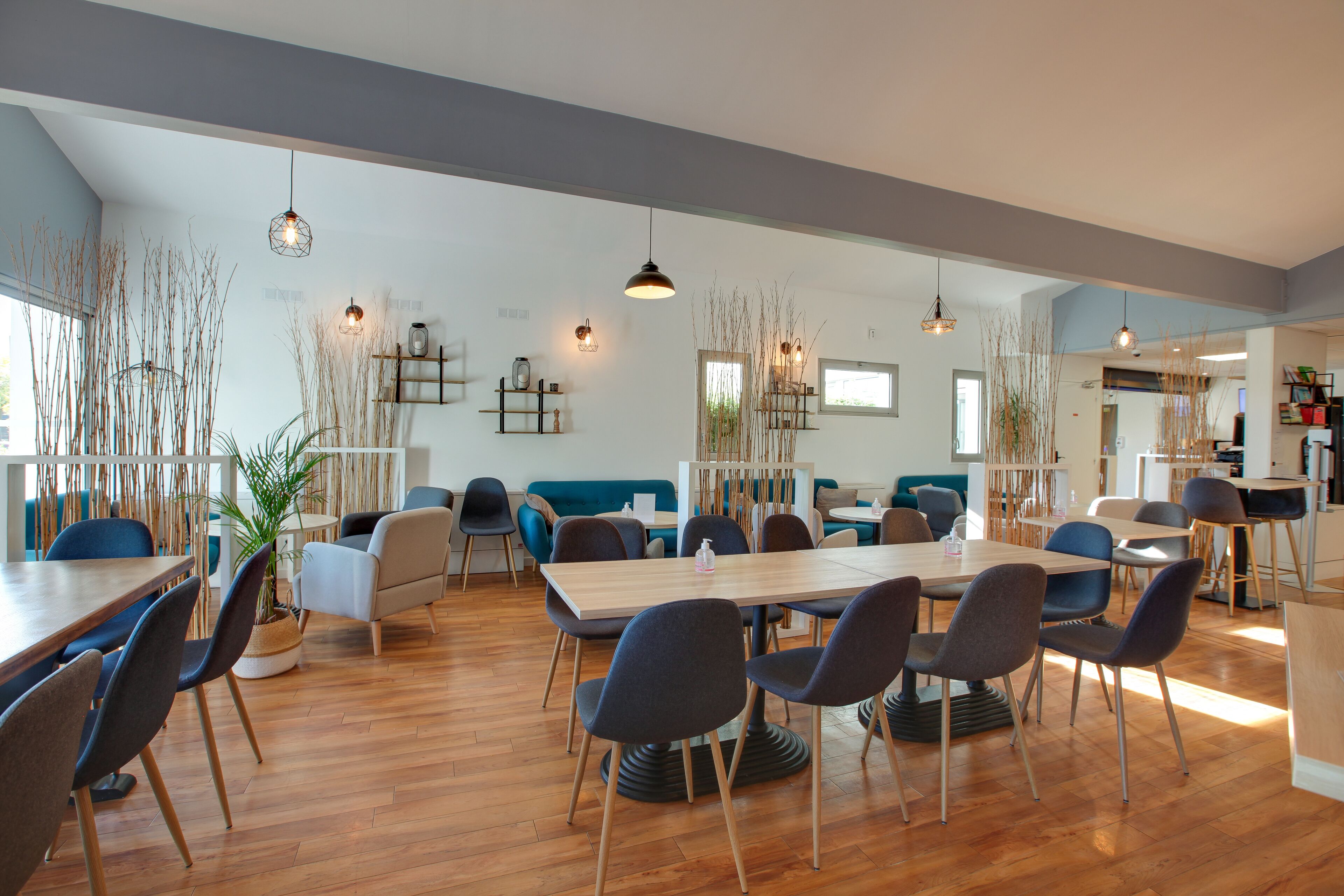Un amplio comedor con mesas altas y sillas modernas, bañado por la luz natural y decorado con plantas de interior.