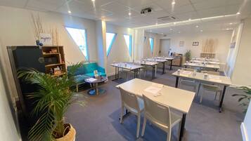 Une salle de conférence moderne, équipée de tables, de chaises et d’un canapé bleu.