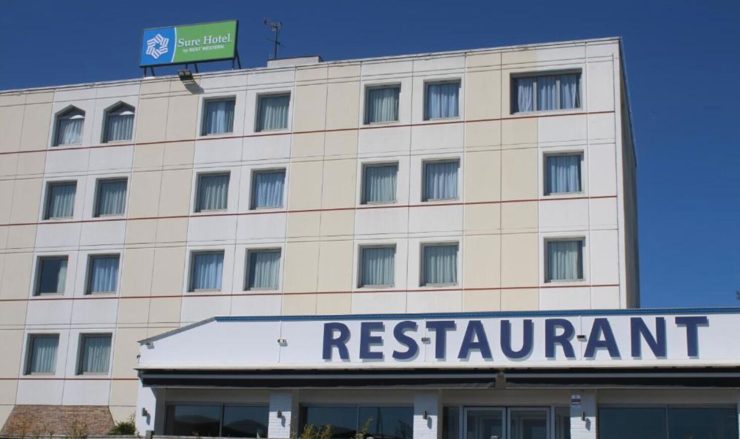 Un hôtel avec une enseigne indiquant la présence d’un restaurant au rez-de-chaussée.