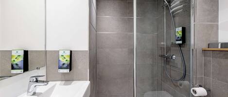 A modern bathroom with a glass-enclosed shower, a white sink, and a toilet.