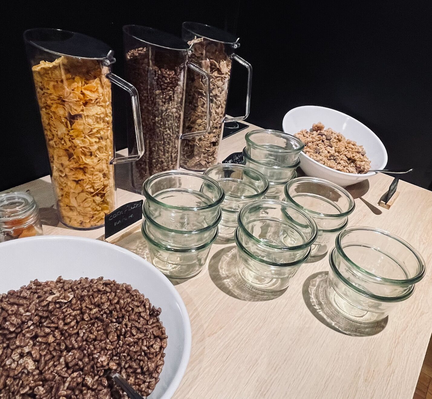 Une table sur laquelle se trouvent divers aliments, notamment des bols et des bocaux de céréales et de granola.