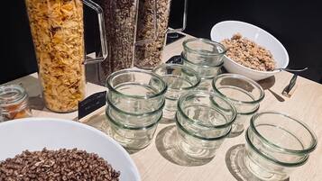 Une table sur laquelle se trouvent divers aliments, notamment des bols et des bocaux de céréales et de granola.