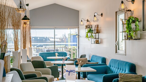 A modern lounge area with seating, tables, and decorative plants. - Sure Hotel by Best Western Bordeaux Lac (Bordeaux)