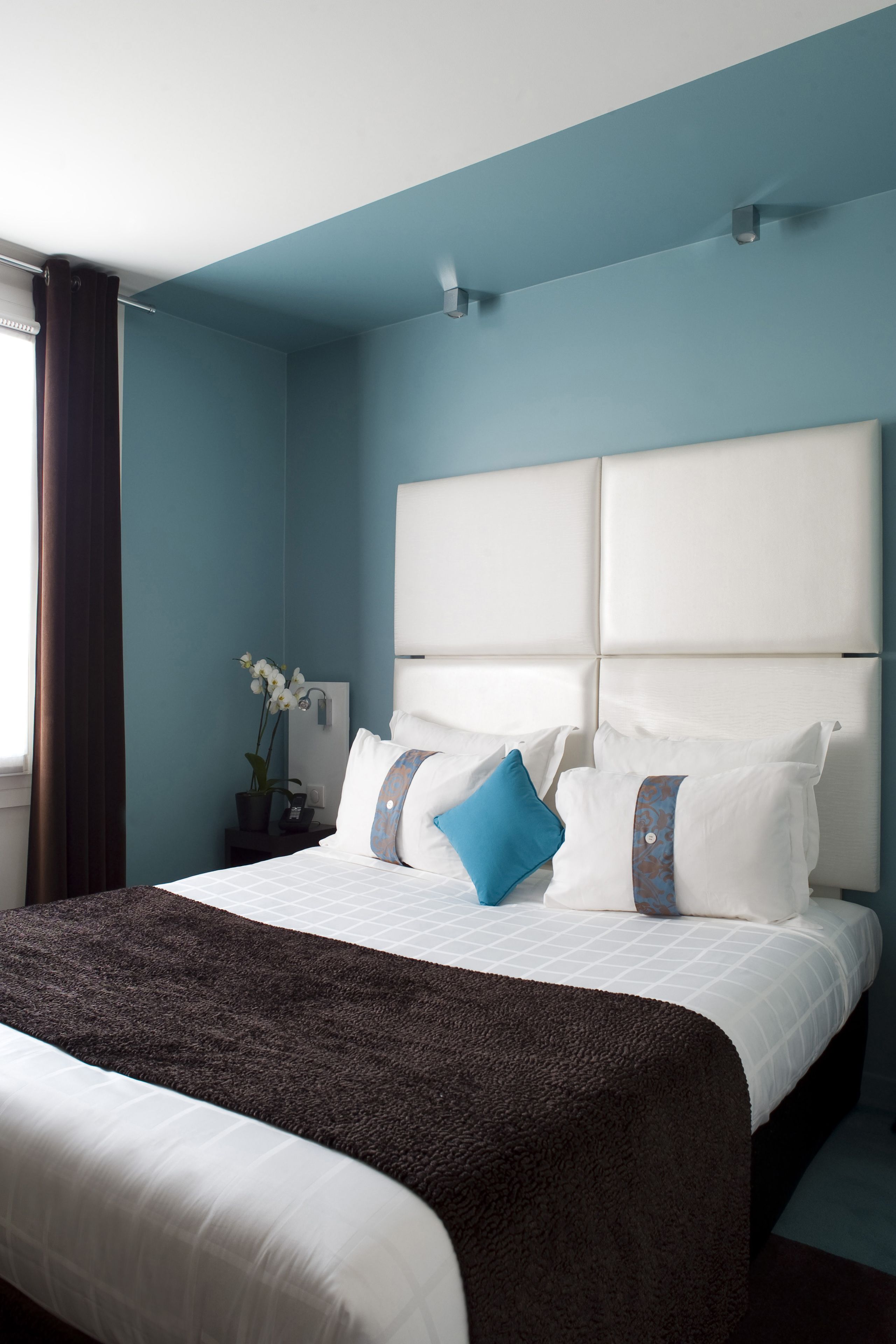 A hotel room with a large bed, a headboard, and a window with curtains.