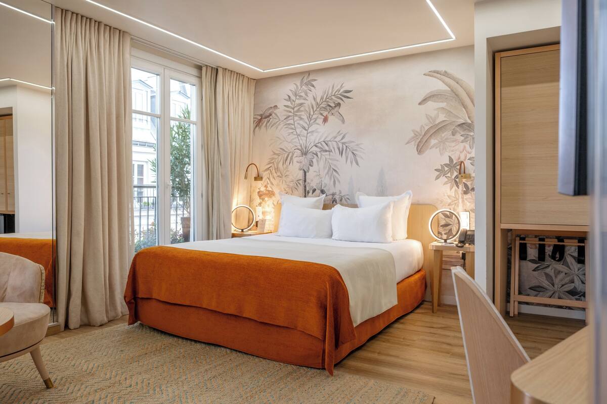 A modern hotel room with a large bed, a sitting area, and a view of the city.