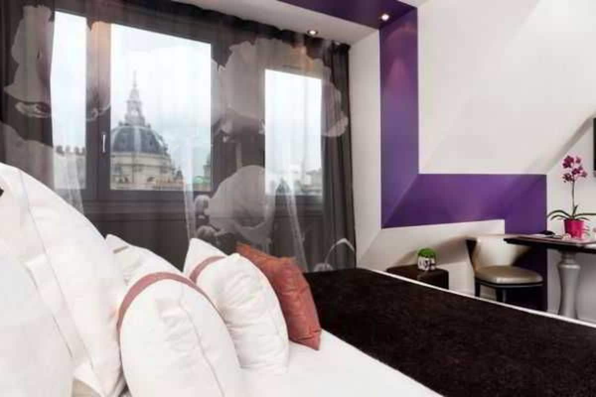 A modern hotel room with a large bed, a desk, and a TV.