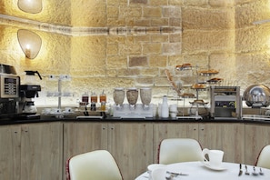 A breakfast bar with coffee machines, a fruit display, and seating for guests. - Grand Hotel Saint Michel (Paris)