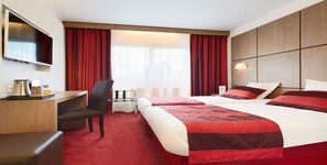 A hotel room with two beds, a desk, a chair, a TV, and a window with red curtains. - Kyriad Grenoble Centre (Grenoble)
