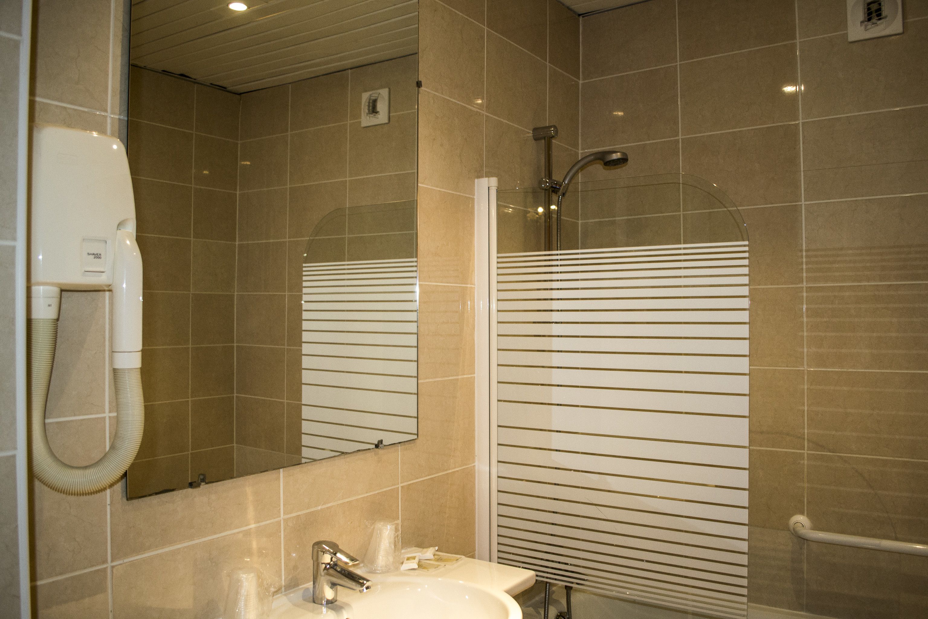 A bathroom with a sink, mirror, and shower.
