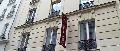 Un bâtiment sur lequel on peut lire l’inscription « HÔTEL TOURING » et qui est doté d’auvents portant le même nom.