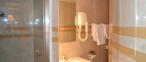 Un baño con lavamanos, espejo, toallero y zona de ducha.
