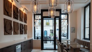 Una cocina moderna con una isla central, iluminación colgante y vistas a la calle a través de amplios ventanales.
