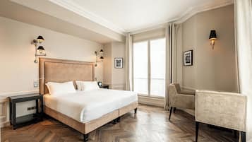 A hotel room with a large bed, two bedside tables, a chair, and a large window with curtains.