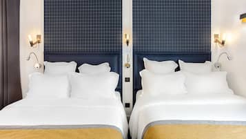 Ein Hotelzimmer mit zwei Betten, einem dunkelblauen Kopfteil und Wandleuchten.