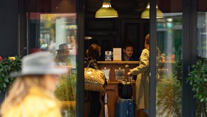 A hotel entrance with a reception desk, a blue suitcase, and a person in a yellow coat. - Hôtel Clarisse (Paris)