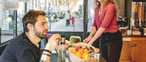 Un comedor moderno con una mesa de madera, un cuenco de frutas y una cafetera.