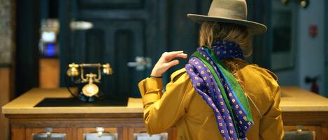 A person in a yellow jacket and hat standing in a room with a wooden counter and two green pendant lights.
