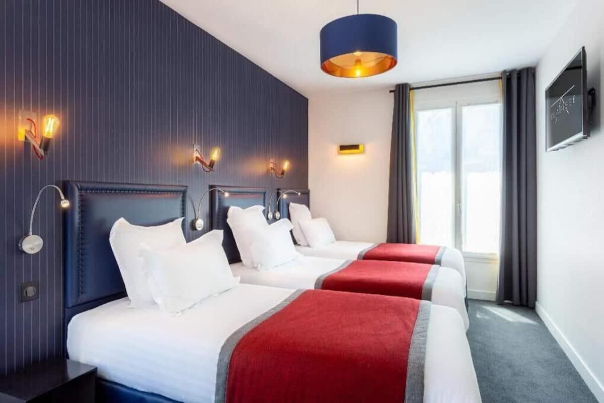 A hotel room with three beds, a TV, and a large window.