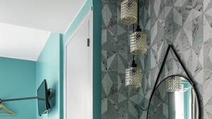 A teal-walled room with a mirror, pendant lights, and a chair. - Hôtel Elysée Etoile (Paris)