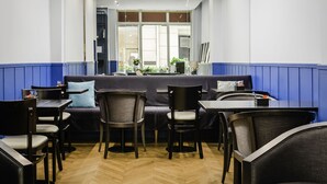A restaurant with a blue and white color scheme, featuring a sofa and multiple tables and chairs. - Hôtel Elysée Etoile (Paris)