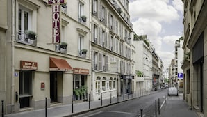 A hotel with a prominent 'HOTEL' sign, multiple balconies with plants, and a cobblestone street. - Hôtel Elysée Etoile (Paris)